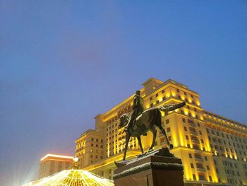 Low angle view of illuminated buildings against blue sky