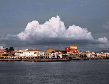 Sea by buildings against sky in city