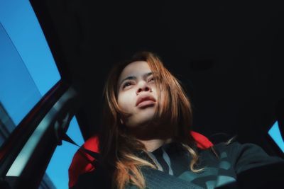 Low angle view of woman looking away while sitting in car