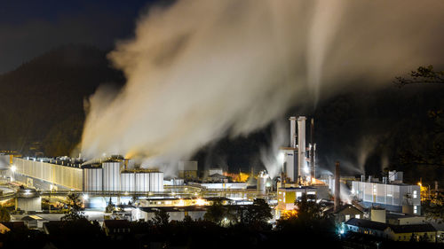 Illuminated factory against sky at night