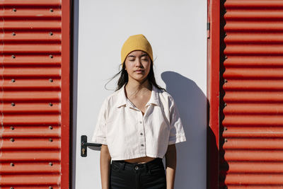 Woman wearing knit hat standing with eyes closed on sunny day