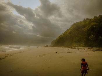 Rear view of woman on beach against sky