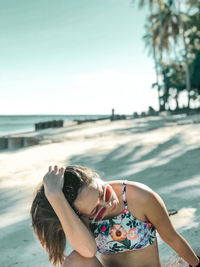 Young woman in swimming pool at beach against clear sky