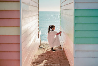 Woman standing on wall by sea