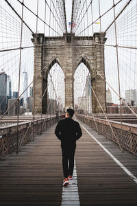 Rear view of man walking on bridge