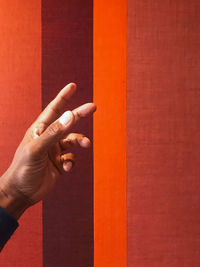 Cropped hand of man against red wall