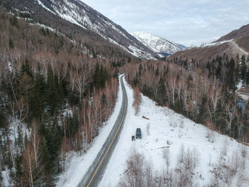 Snow covered road by mountain against sky