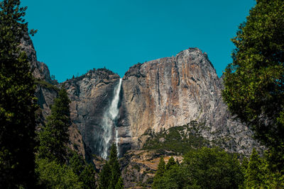 Low angle view of waterfall against clear sky