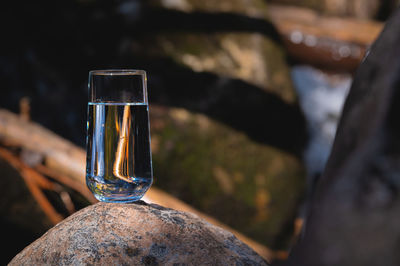 Glass of water on stones and a river in the background. nature blur background