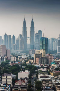 Petronas towers by residential district against sky