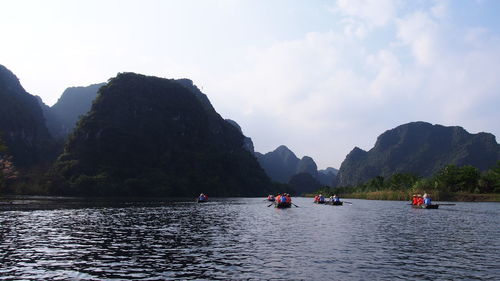 Boats in sea with mountain range in background