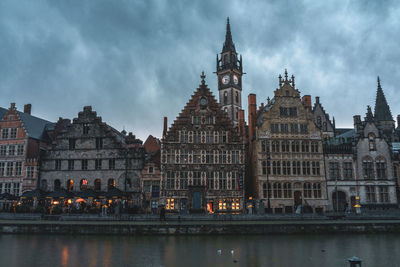 Buildings in city against cloudy sky