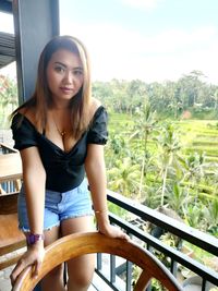 Portrait of young woman sitting on railing