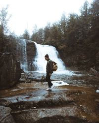 Side view of man standing by waterfall