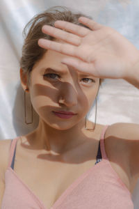 Close-up portrait of young woman shielding eyes