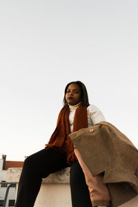 Portrait of young woman standing against white background