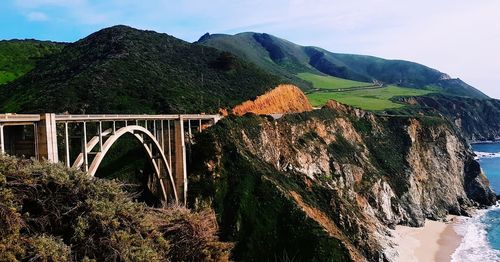 Arch bridge over mountains against sky