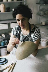 Craftswoman painting bowl at ceramics store