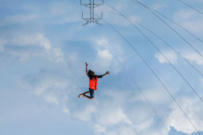 Upside down image of man flying against cloudy sky