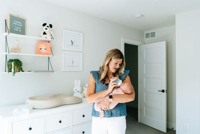 Straight on portrait of a new mom bottle feeding her baby girl