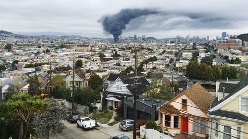 Smoke emitting amidst cityscape against sky