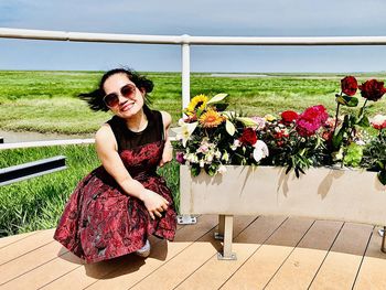 Portrait of young woman smiling by flowering plants