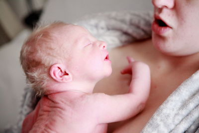 Cropped image of mother carrying newborn baby at home