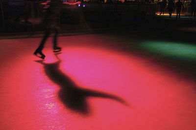 Low section of silhouette woman walking on illuminated floor