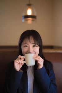 Portrait of smiling businesswoman drinking coffee while sitting in restaurant