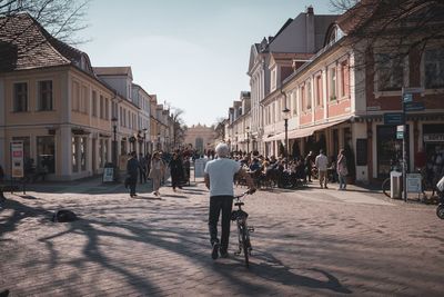 People walking on street amidst buildings in city