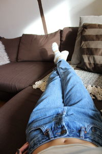 Low section of man sitting on sofa at home