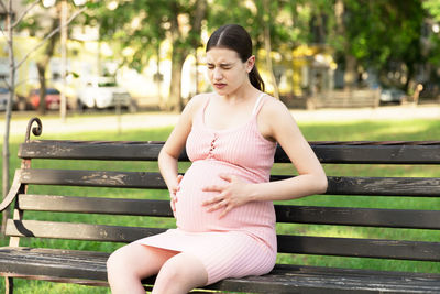 Young woman sitting on bench in park