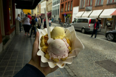 Person holding ice cream cone on street in city