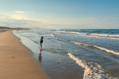Full length of girl standing beach against sky