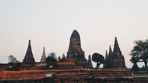 Old temple against buildings against clear sky