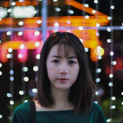 Portrait of woman against illuminated string lights