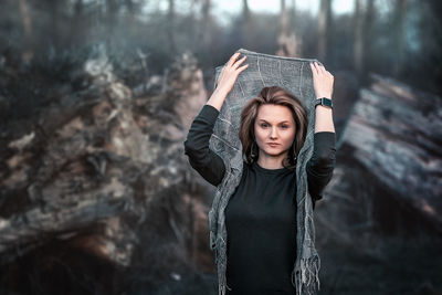 Portrait of young woman standing against trees