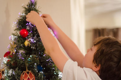 Close-up of boy decorating christmas tree at home