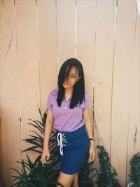 Portrait of beautiful woman standing against wooden wall