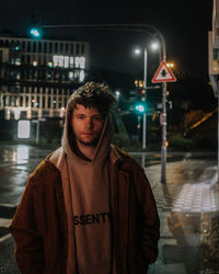 Portrait of young man standing on street at night