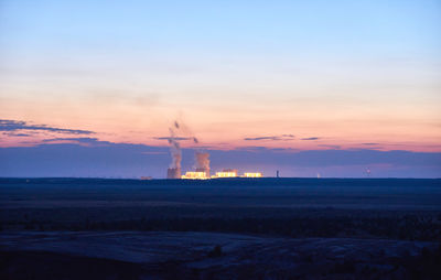 Factory against sky at sunset