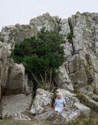 Woman sitting on rock by mountain