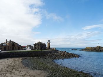 Buildings by sea against sky