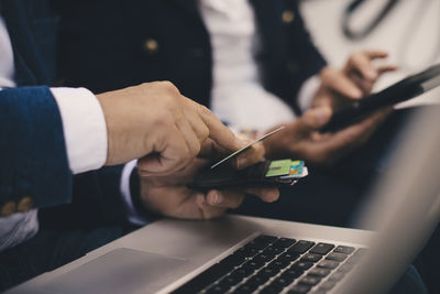 Cropped image of senior man holding credit card while doing online shopping in yacht