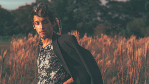 Portrait of young man looking away on field