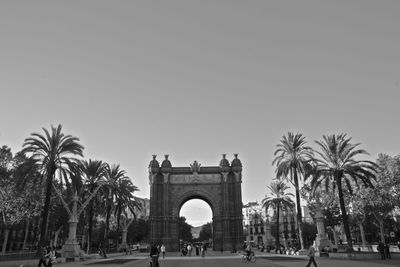 People at historic arc de triomf against sky