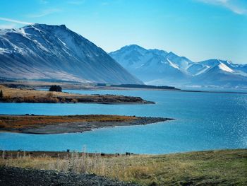 Scenic view of lake and mountains against blue sky