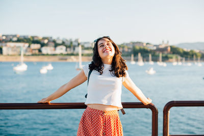 Happy woman standing against sea