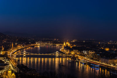 Illuminated bridge over river in city at night