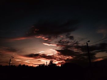 Low angle view of silhouette trees against dramatic sky